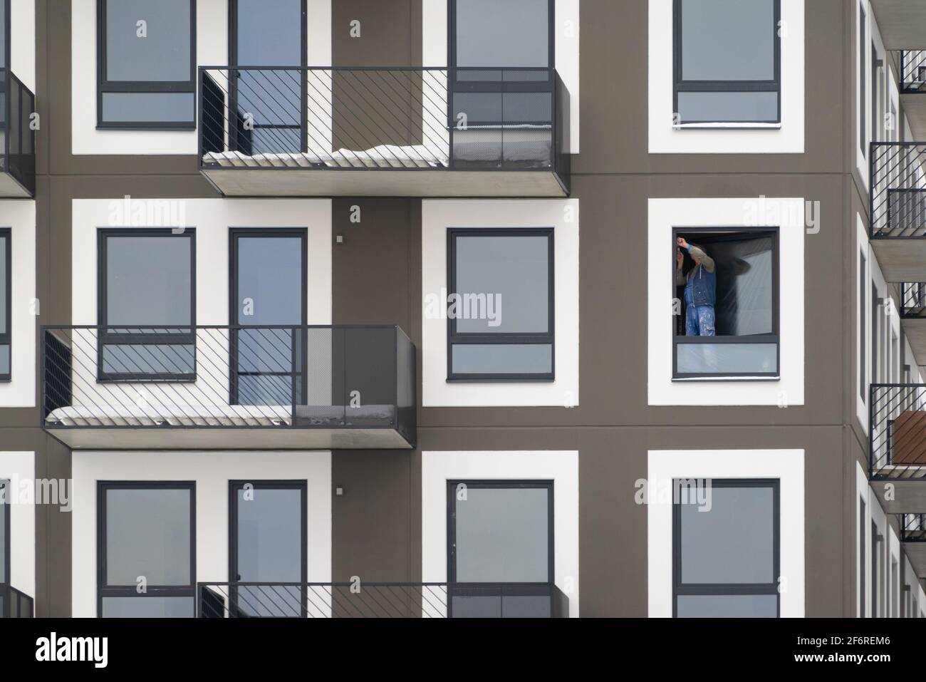 Falegname che installa una finestra in alto in un condominio. Appaltatore che fissa una finestra di vetro. Foto Stock