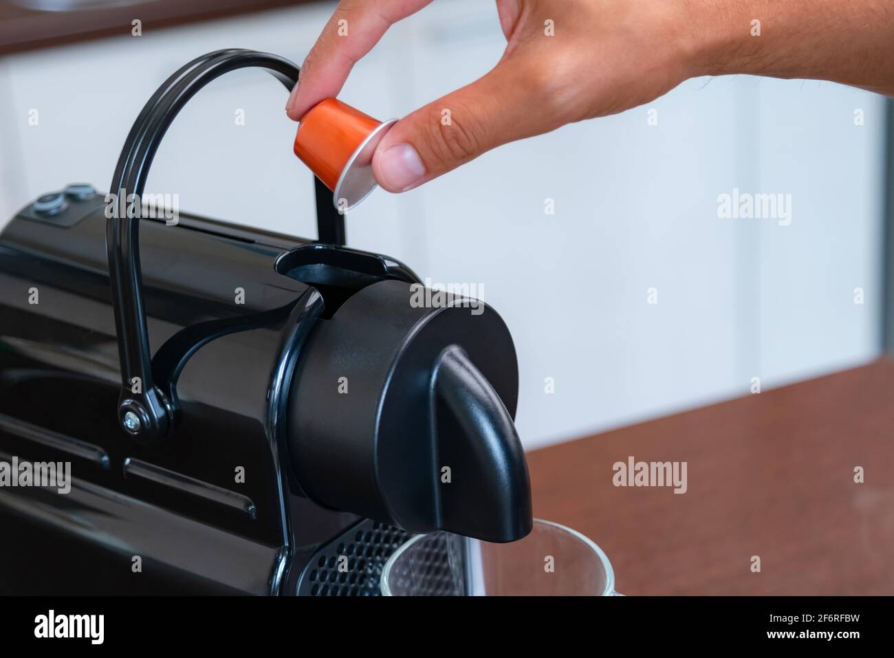 Primo piano di una mano che inserisce una capsula in una macchina da caffè a casa. Concetto di pausa caffè. Foto Stock