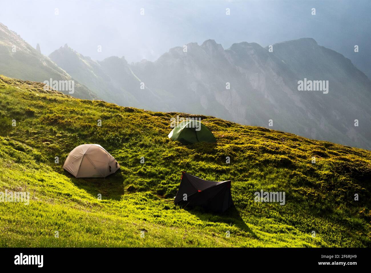 Tre tende turisti accampano su un prato incredibile in montagna primavera. Fotografia di paesaggi, concetto di viaggio Foto Stock