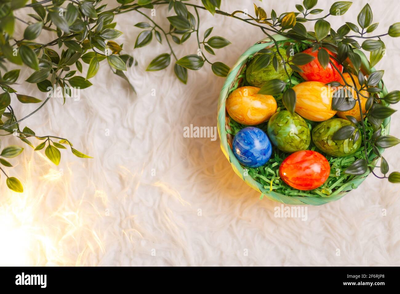 Carta di Pasqua. Composizione piatta con uova di pasqua in un cesto su sfondo bianco. Foto Stock