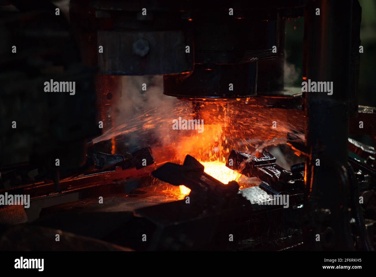 Impianto di cuscinetti. Stampaggio dell'anello del cuscinetto su pressa meccanica e raffreddamento ad acqua del metallo. Metallo rosso-caldo. Primo piano della foto. Foto Stock