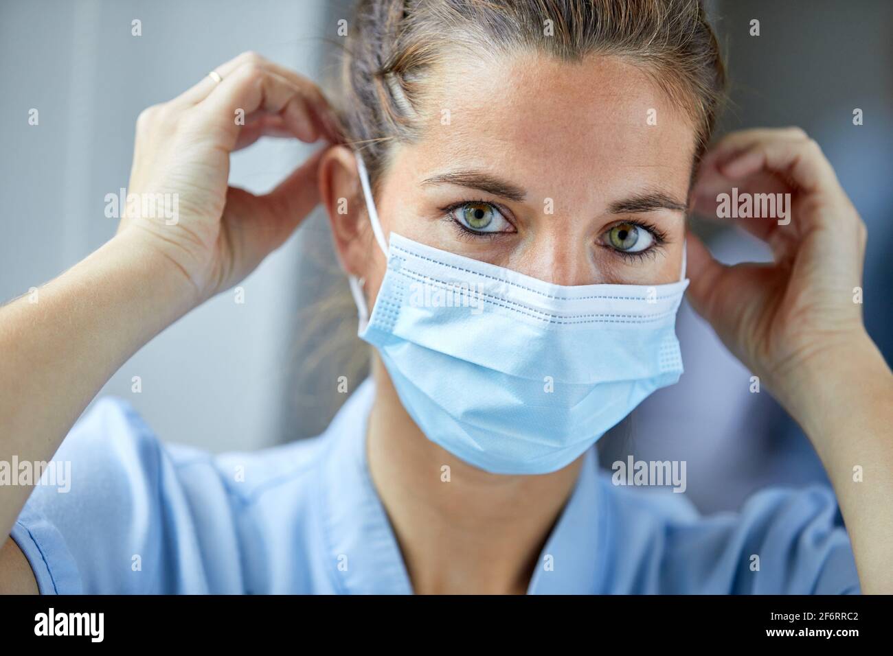 Ritratto di operatrice sanitaria femminile che mette su maschera protettiva, infermiera, Ospedale Foto Stock