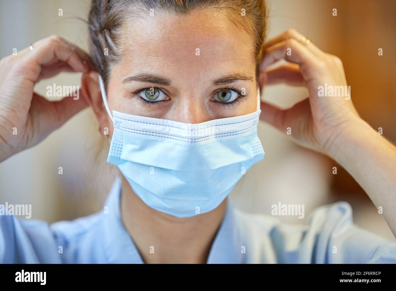 Ritratto di operatrice sanitaria femminile che mette su maschera protettiva, infermiera, Ospedale Foto Stock