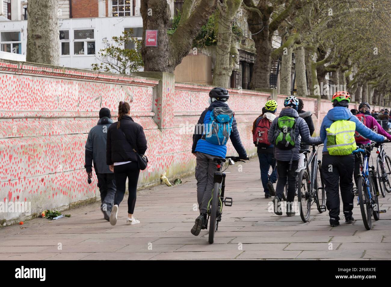 Gruppi di ciclisti e residenti locali camminano e visitano il muro commemorativo del covid nazionale, la riva sud di Londra, sull'argine, Inghilterra Foto Stock