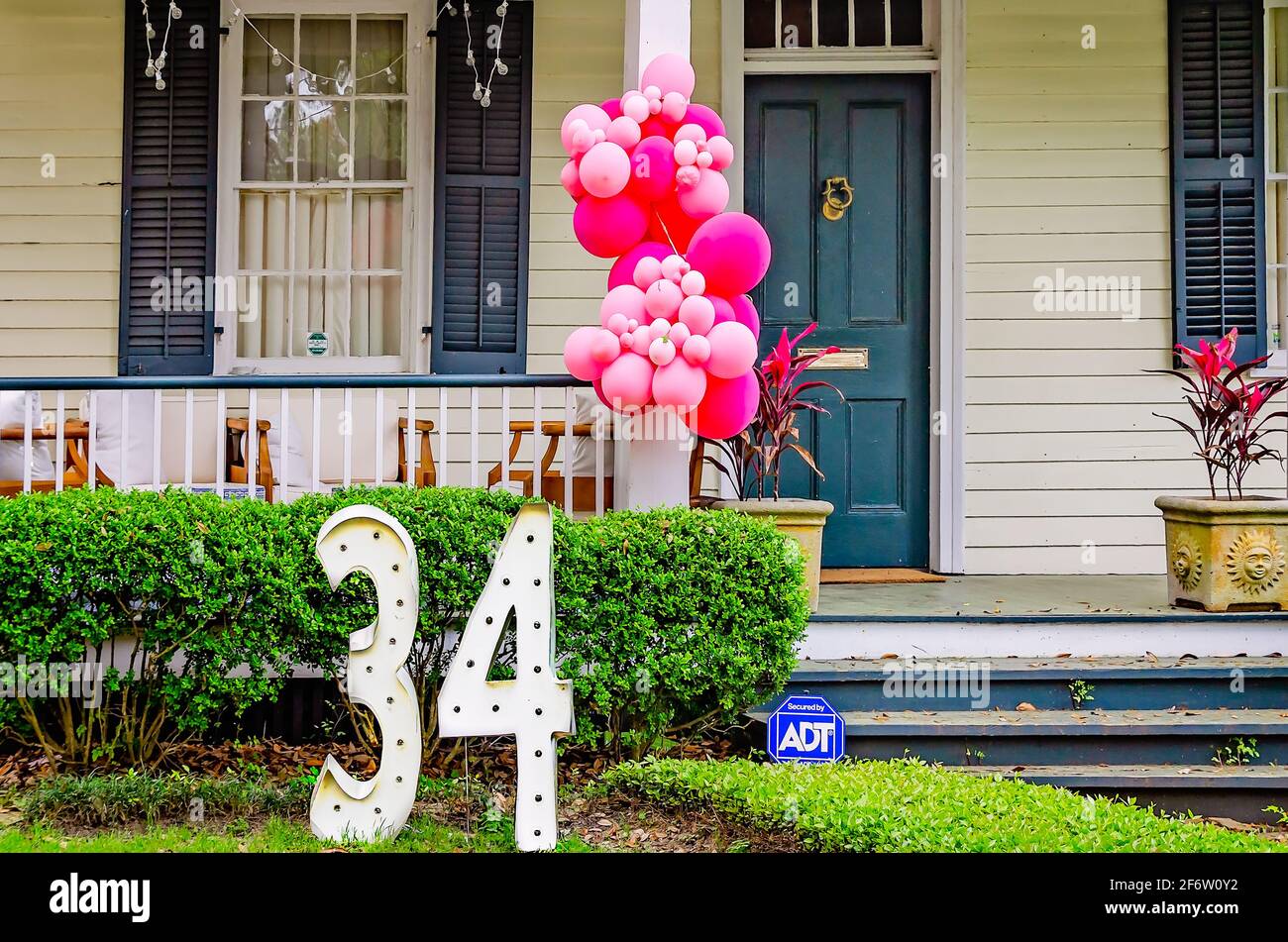 Palloncini appesi a una ringhiera porticato e un gran numero "34" sul prato segnano il compleanno di un residente locale, il 30 marzo 2021, a Mobile, Alabama. Foto Stock