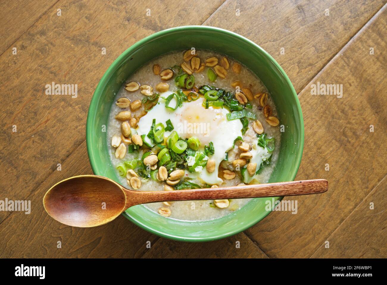 ciotola di alghe o porridge di riso con uovo verde fritto cipolle e arachidi Foto Stock