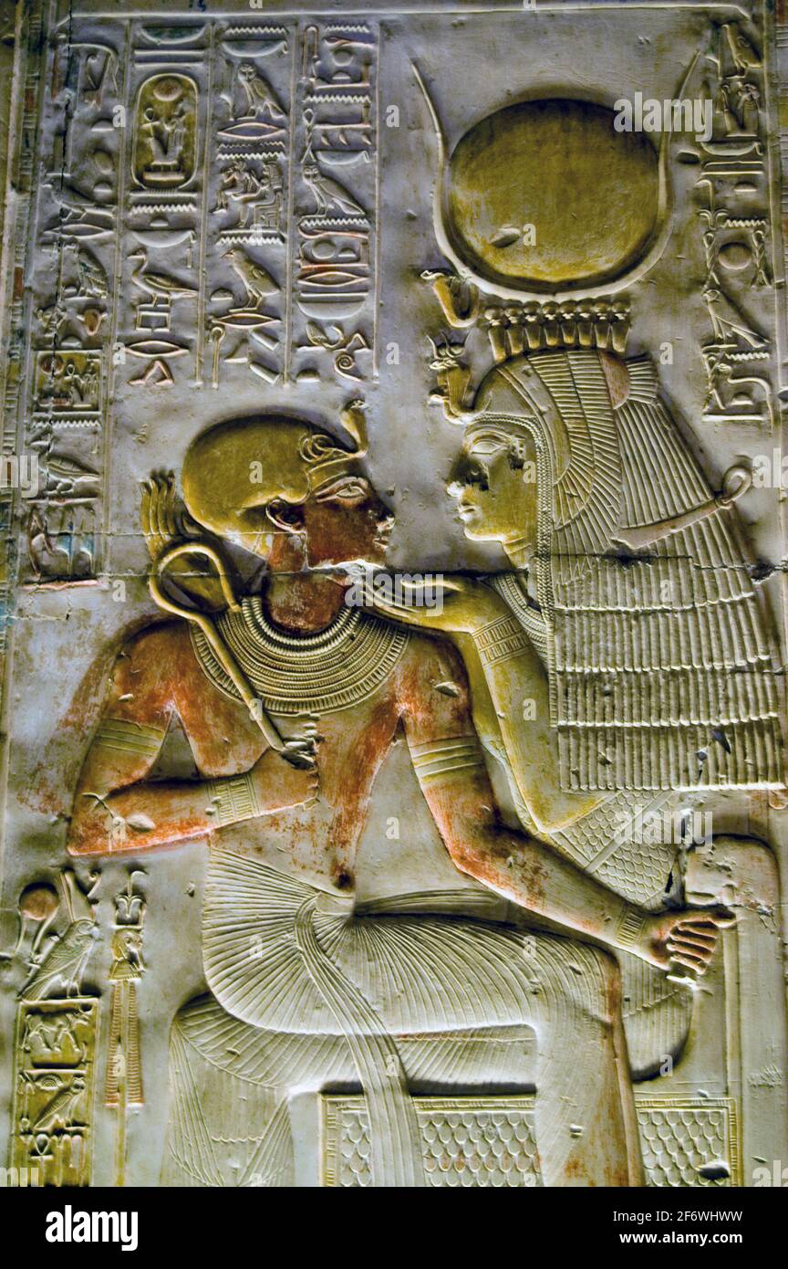 Un'antica scultura geroglifica egiziana che mostra la dea Iside - con la corona di Hathor - con la giovane faroah Seti in grembo. Parete del Foto Stock