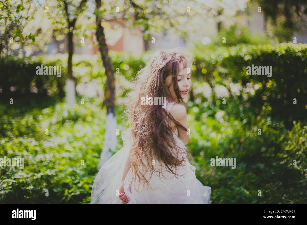 Bambina in giacca nera e abito bianco danzare il giardino di ciliegio primaverile Foto Stock