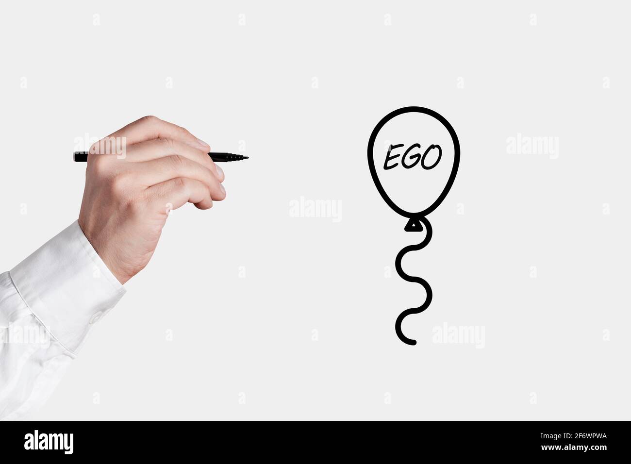 L'uomo d'affari con una penna sta per schioccare un'icona del palloncino con la parola ego. Abbassare o liberare il tuo concetto ego. Foto Stock