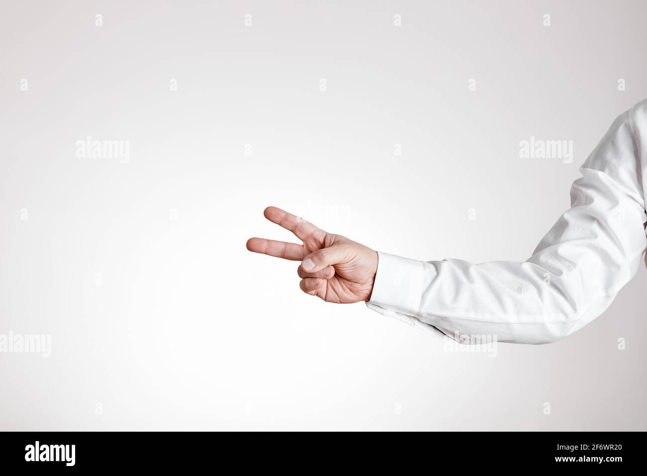 La mano dell'uomo d'affari fa il gesto della vittoria su sfondo bianco con lo spazio di copia. Foto Stock