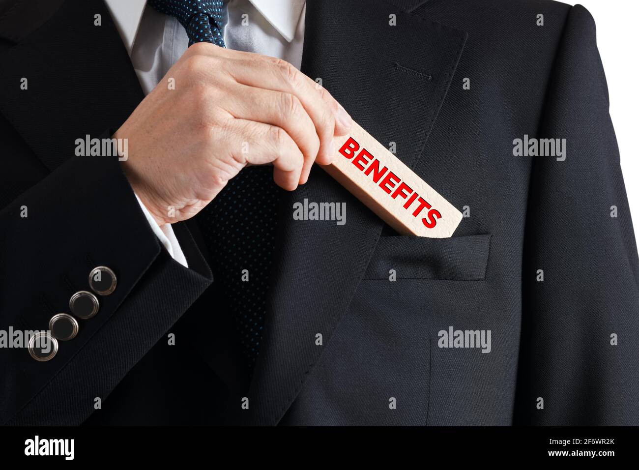 Uomo d'affari toglie un blocco di legno dalla sua tasca con la parola benefici. Concetto di benefici professionali aziendali. Foto Stock