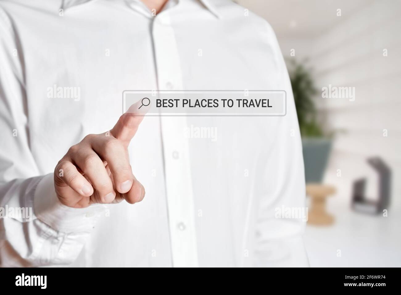 Uomo premere l'icona della barra di ricerca su uno schermo virtuale con la parola luoghi migliori per viaggiare. Ricerca online delle località di viaggio su Internet Foto Stock