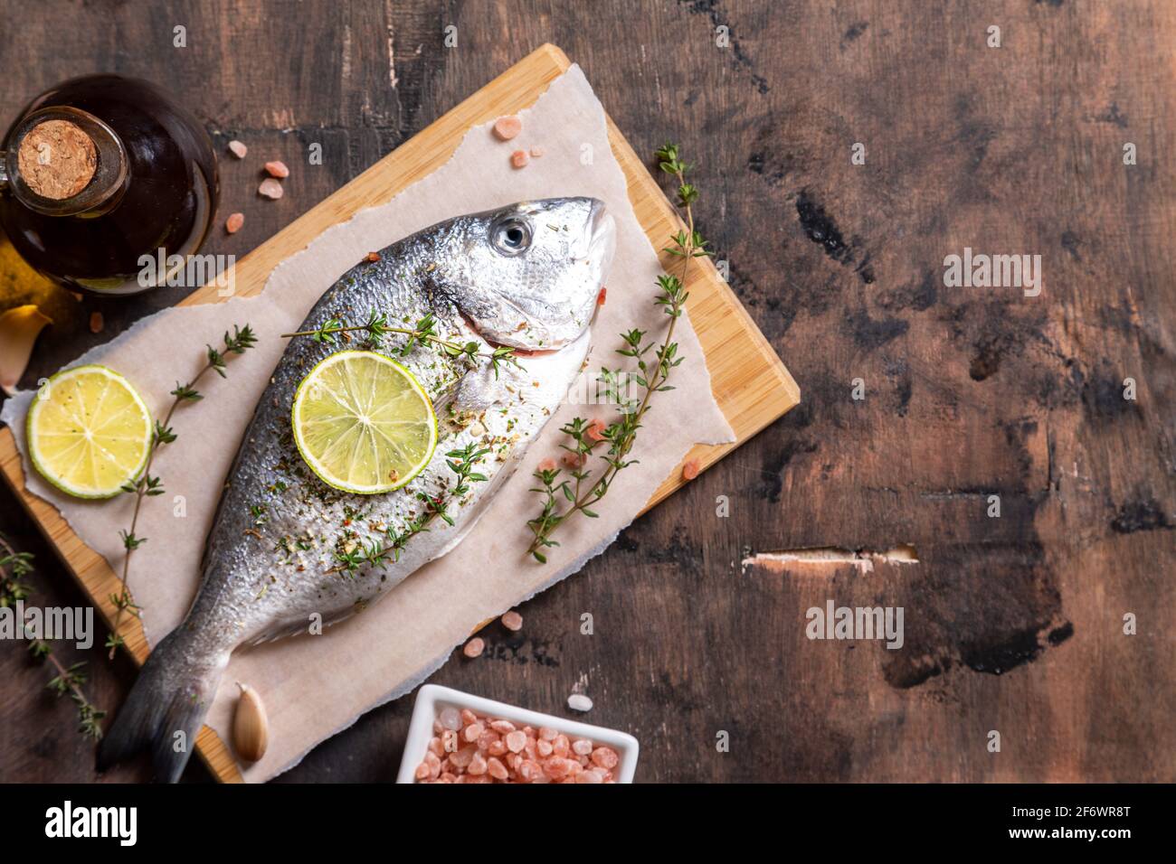 pesce dorado fresco crudo, pesce dorado e ingredienti da cucina - lime, sale, olio, aglio, timo ed erbe Foto Stock