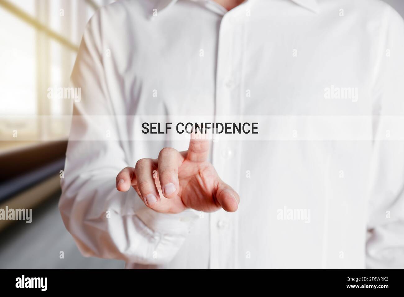 Mano di uomo d'affari preme sulla parola fiducia di sé su un touch screen virtuale. Fiducia in se stessi o stima nel concetto di affari o di carriera. Foto Stock