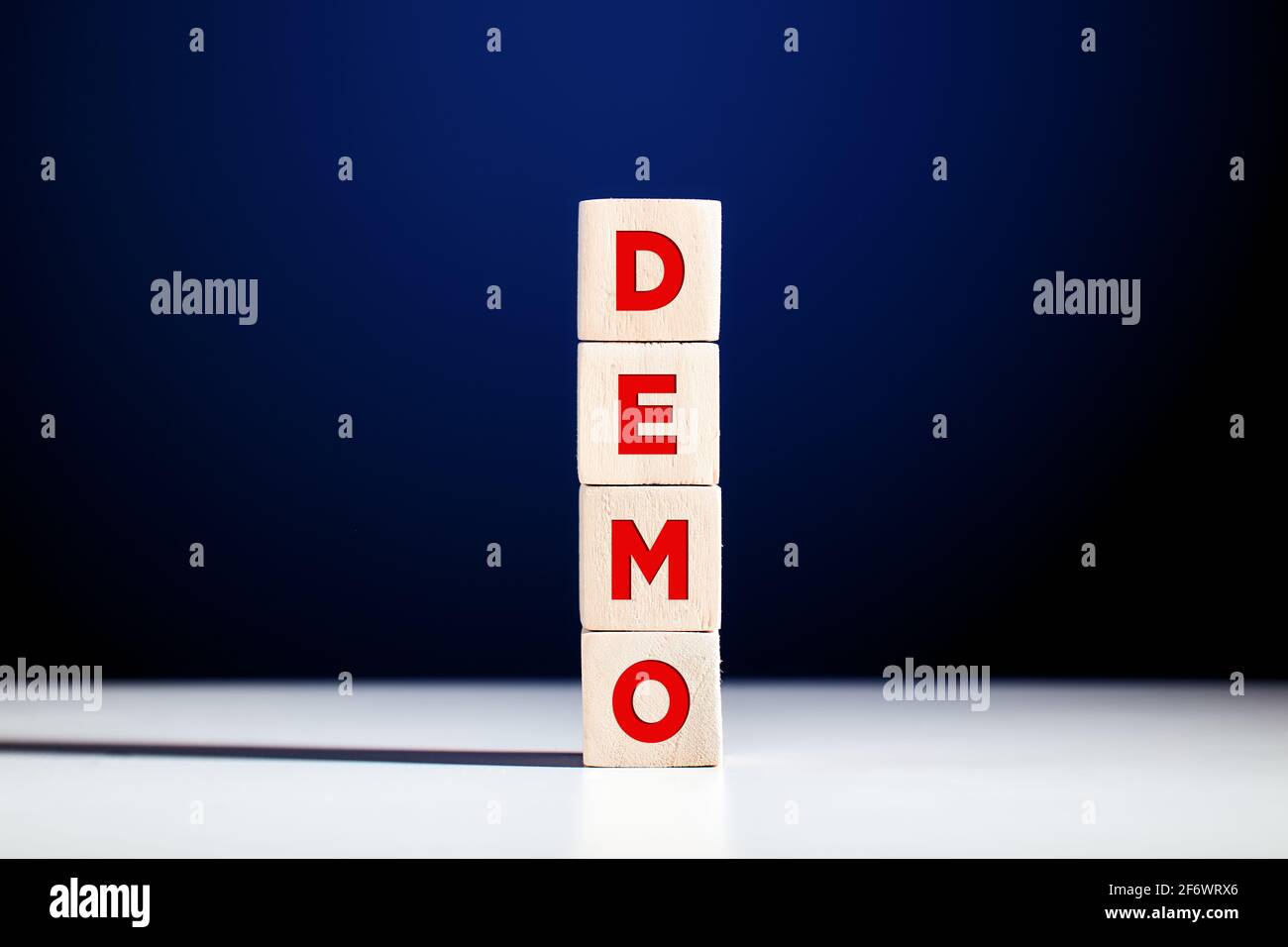 La parola demo scritta su cubi di legno a più livelli su sfondo blu. Acronimo di dimostrazione. Foto Stock