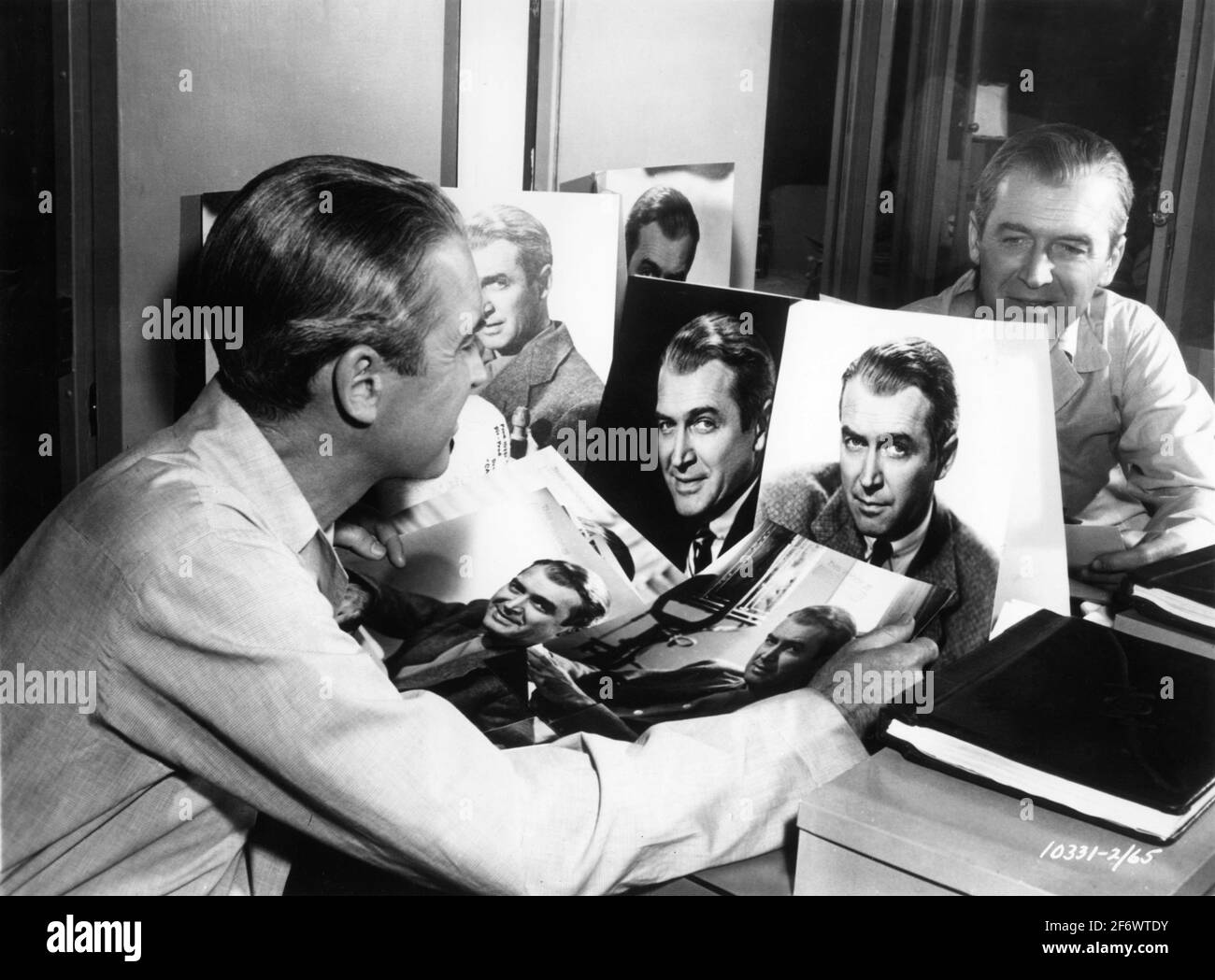 JAMES STEWART controlla i nuovi ritratti pubblicitari di se stesso nella sua cameretta durante le riprese della FINESTRA POSTERIORE 1954 regista ALFRED HITCHCOCK sceneggiatura John Michael Hayes basato su una breve storia di Cornell Woolrich Alfred J. Hitchcock Productions / Paramount Pictures Foto Stock
