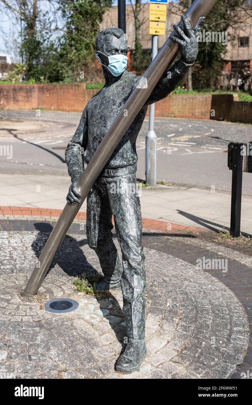 Statua di un uomo che indossa una maschera medica blu durante la pandemia di Coronavirus Covid-19 - una delle due figure della scultura l'Arc. Basingstoke, Regno Unito Foto Stock