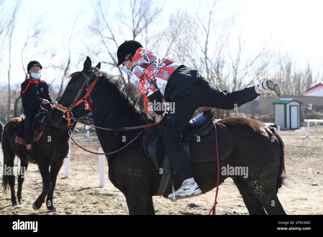 (210403) -- BURQIN, 3 aprile 2021 (Xinhua) -- Parasat Zhumabek (fronte), uno studente di grado senventesimo della Oymak Boarding School, si mette a cavallo durante una classe equestre nella contea di Burqin, nella regione autonoma di Xinjiang Uygur, 30 marzo 2021. La gente nella regione autonoma di Xinjiang Uygur ha una tradizione di allevamento di cavalli e di equitazione. La scuola di imbarco di Oymak ha cominciato ad offrire le classi equestri alla fine del 2019. Gli studenti, la maggior parte dei quali provengono da famiglie di pastori, imparano sia la conoscenza teorica che la pratica di equitazione sulle classi equestri. Dopo le lezioni, gli studenti ottengono fisico più forte Foto Stock