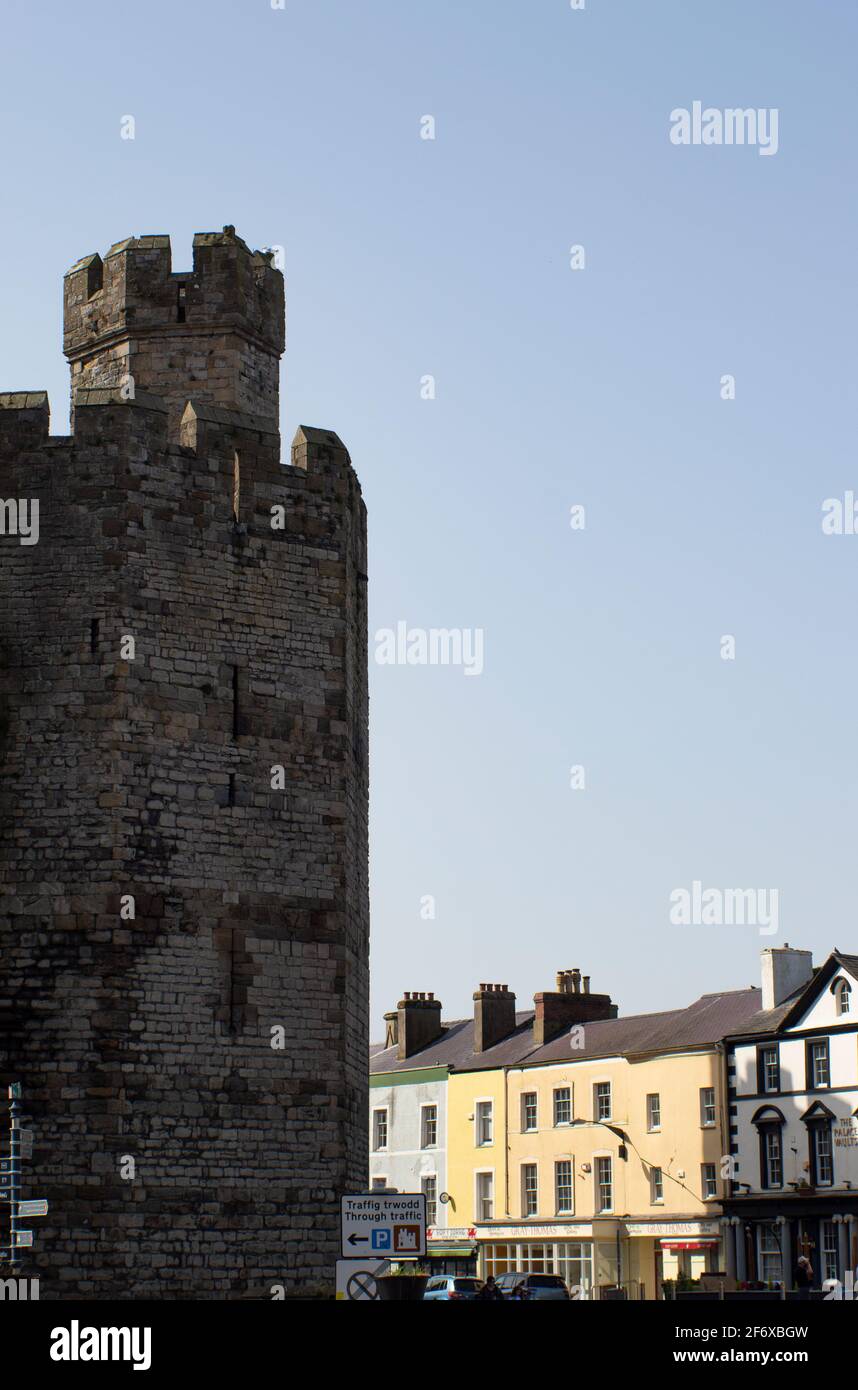 Imponente castello di Caernarfon Galles. Torre fortificata che si erge sopra le case del vecchio quartiere della città reale. Scatto verticale - spazio di copia Foto Stock