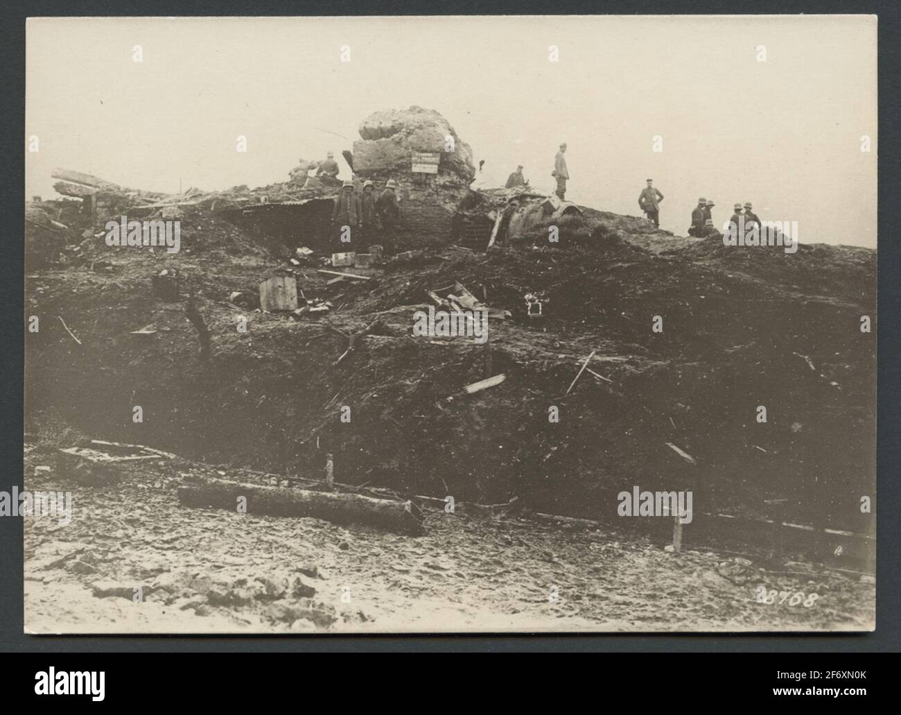 L'immagine mostra un campo di battaglia della prima guerra mondiale. L'area è completamente scavata dall'artiglieria e coperta con le macerie di attrezzature militari. Sullo sfondo, sono visibili un bunker rotto e un gruppo di soldati che ispezionano l'area. L'immagine mostra un campo di battaglia della prima guerra mondiale. L'area è completamente scavata dall'artiglieria e coperta con le macerie di attrezzature militari. Sullo sfondo, sono visibili un bunker rotto e un gruppo di soldati che ispezionano l'area. Foto Stock