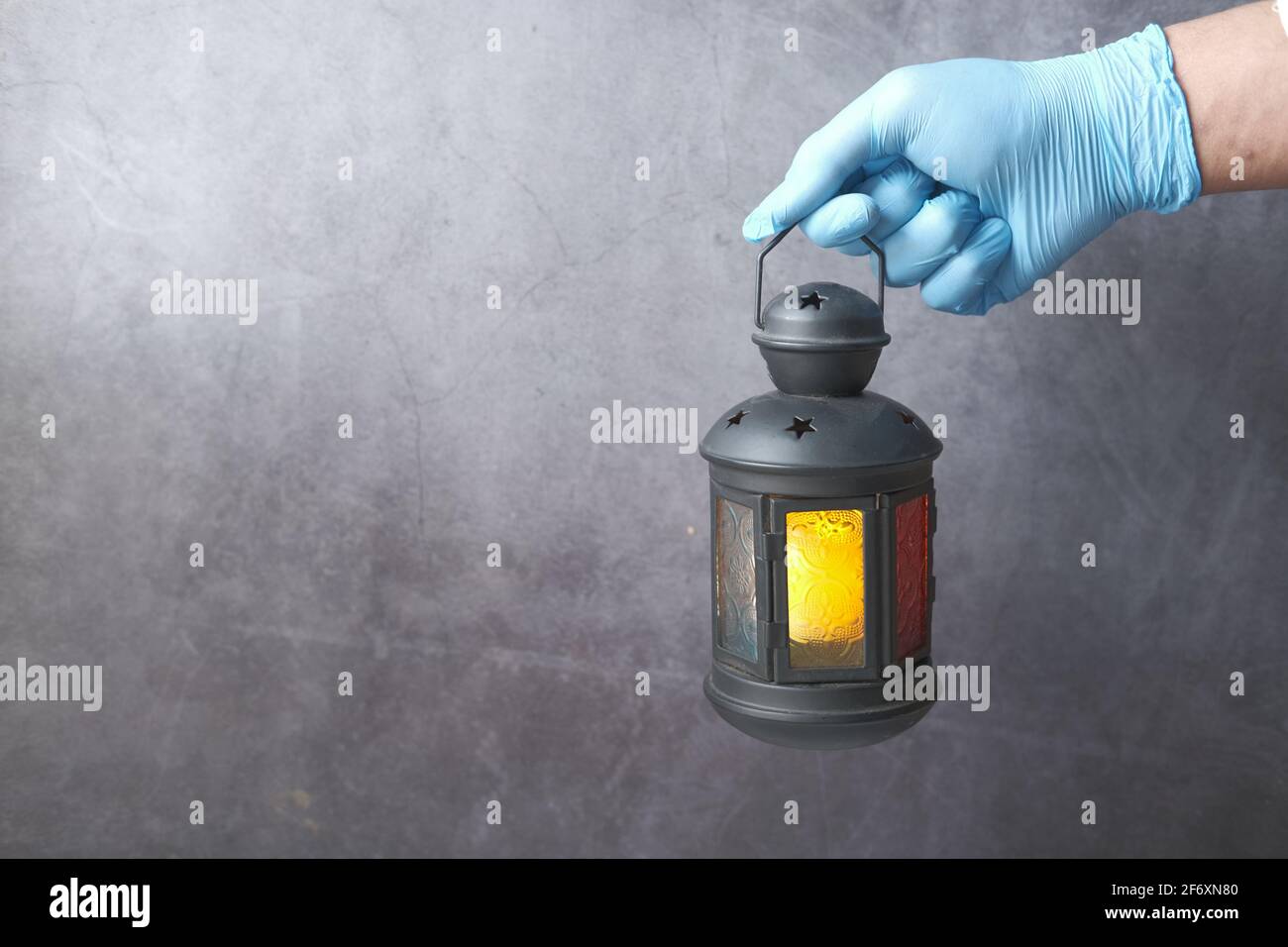 mano in guanti che tengono luce lanterna su sfondo nero . Foto Stock
