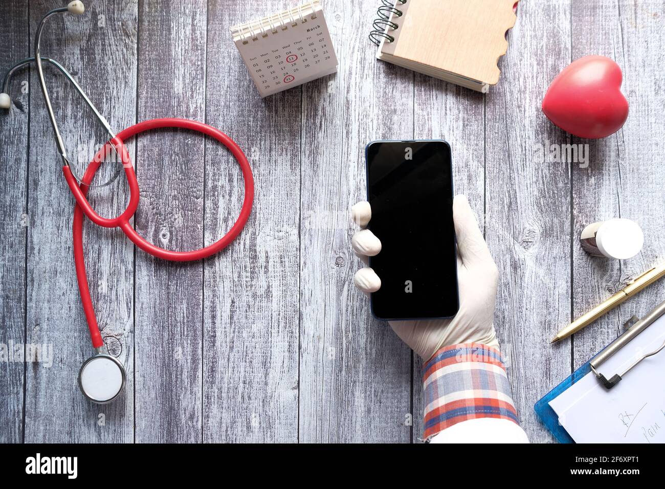 vista dall'alto della mano del medico utilizzando lo smartphone sulla scrivania della clinica Foto Stock
