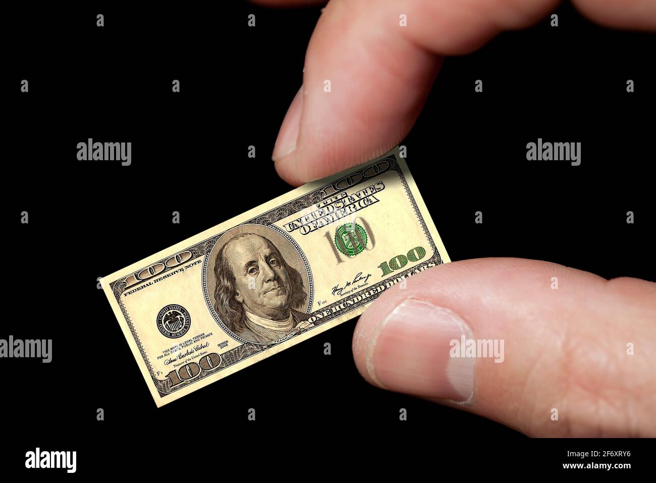 Le dita tengono una piccola nota del dollaro (isolato su nero) Foto Stock