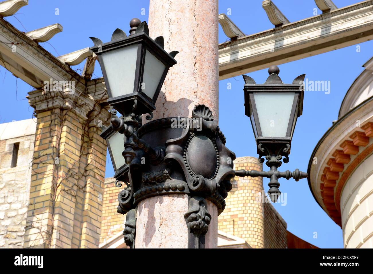 lampade da strada in stile retrò ornate di tipo sconce montate su colonna di pietra. mattoni e pareti di pietra sfondo. cielo blu. architettura classica sorrounding. Foto Stock