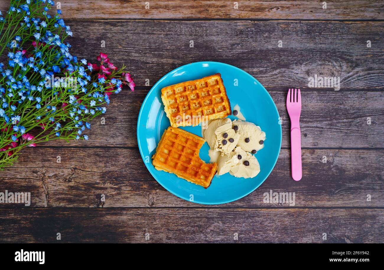 Arriva la primavera: Primo gelato e waffle appena sfornati su un rustico tavolo di legno. Foto Stock