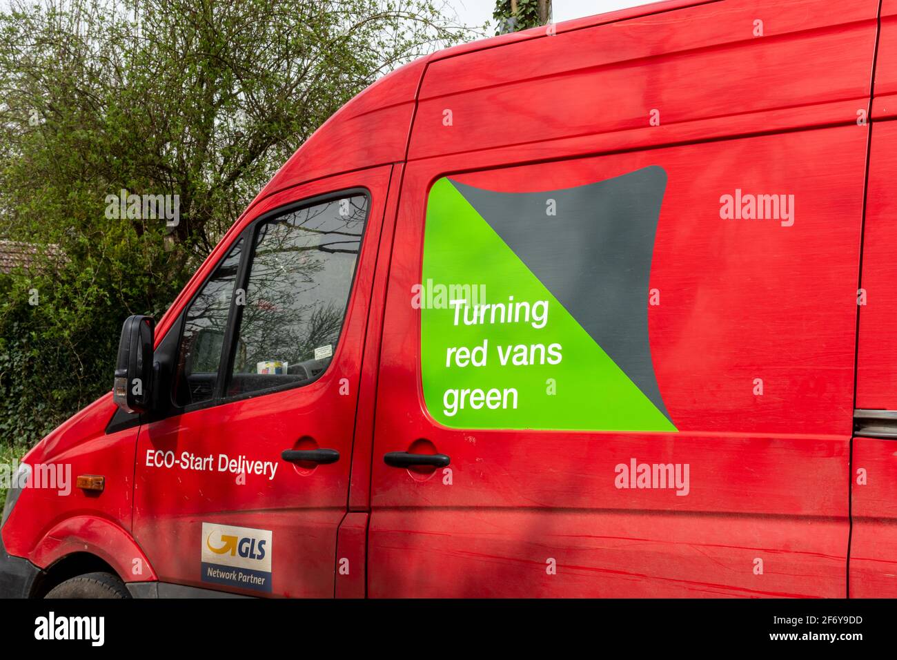 Pulmino rosso Parcelforce in tutto il mondo con uno slogan ecologico Turning Red Vans Green sul lato, Regno Unito Foto Stock