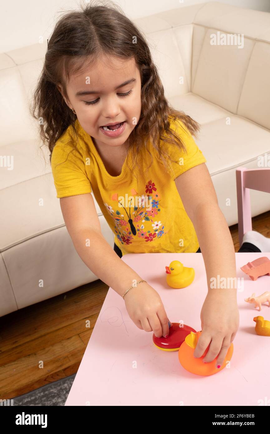 Bambina di quattro anni che gioca con animali giocattolo, parlando con se stessa Foto Stock