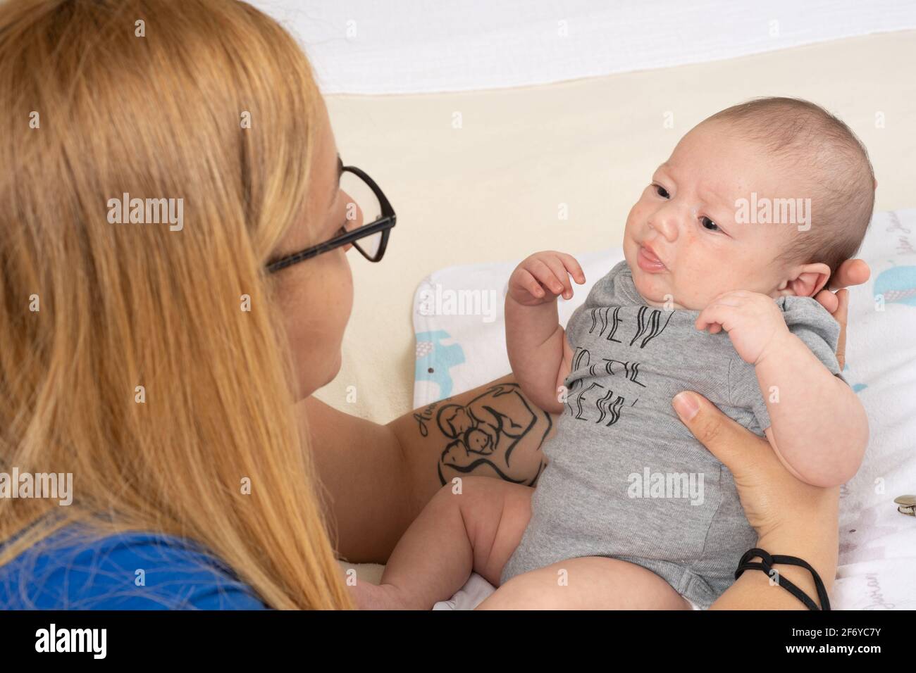 Neonato bambino 7 settimane tenuto da madre, cominciando a irritare Foto Stock