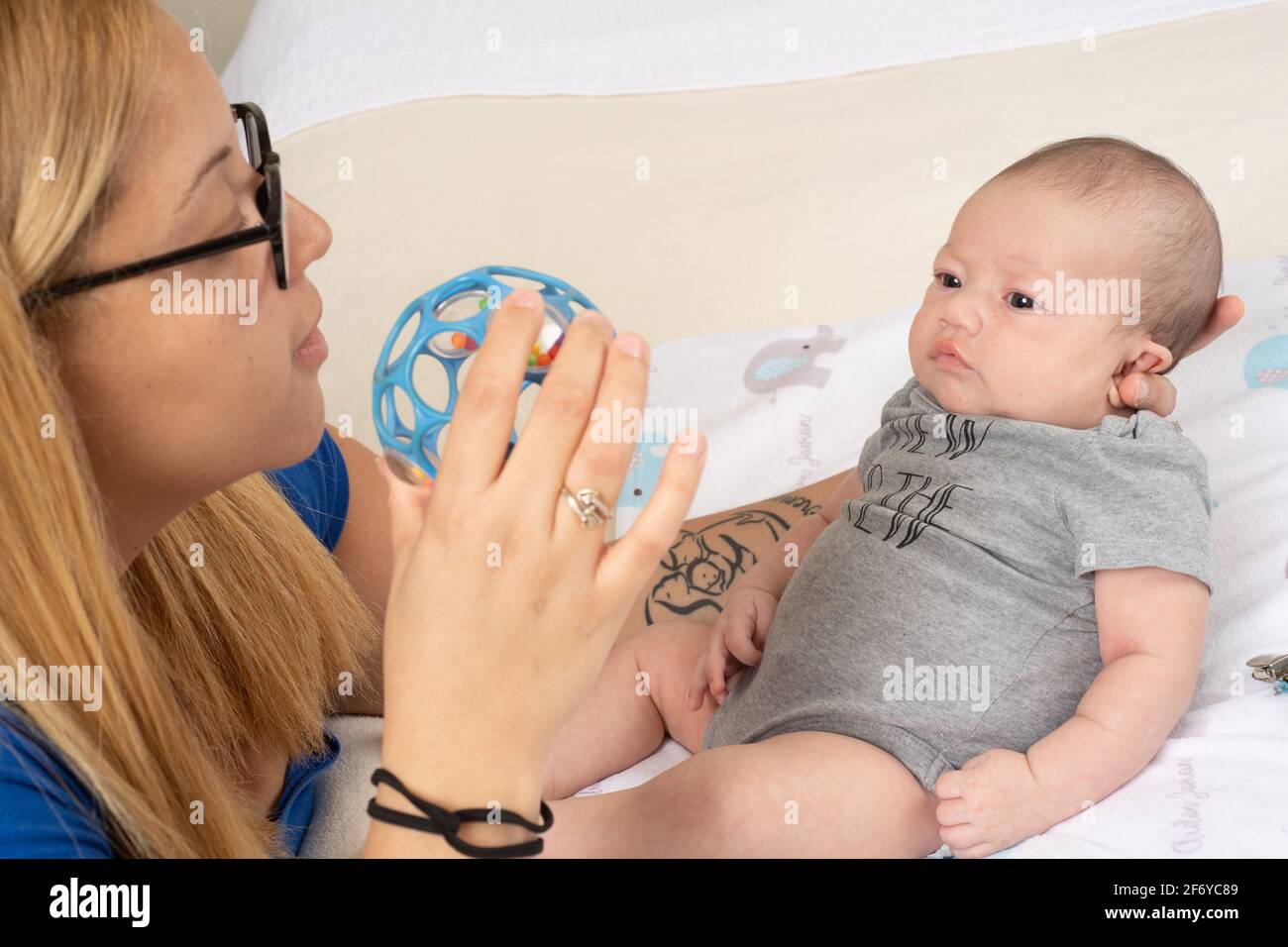 Neonato bambino 7 settimane con madre interessata a. giocattolo che sta tenendo per lui a guardare Foto Stock