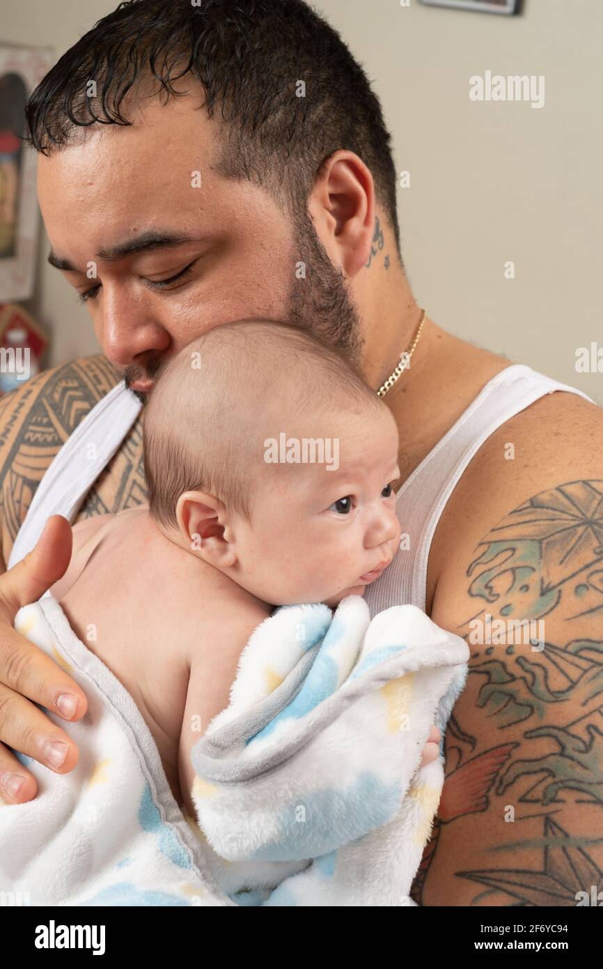 Neonato bambino di 7 settimane avvolto in coperta tenuta dal padre, pattugliato sulla schiena Foto Stock