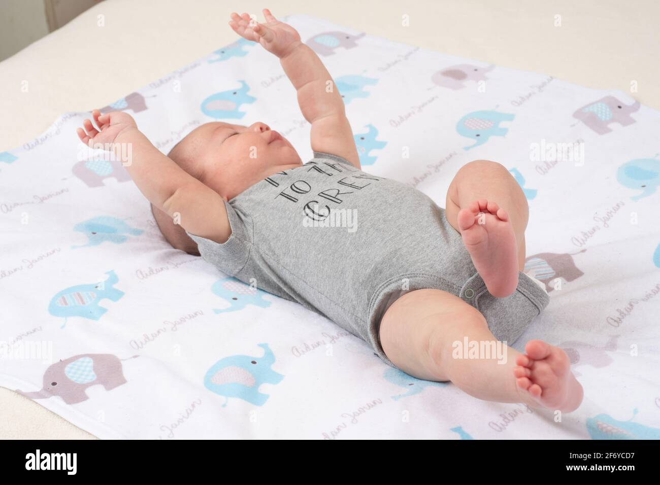 Neonato bambino 7 settimane di età sulle braccia posteriori che si allungano sopra la testa Foto Stock