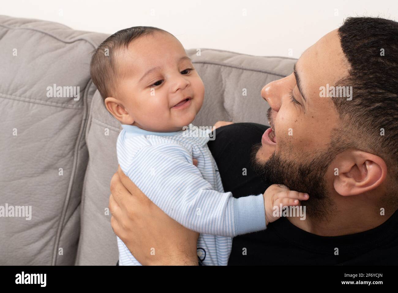 Padre che tiene e interagisce con il bambino di quattro mesi Foto Stock