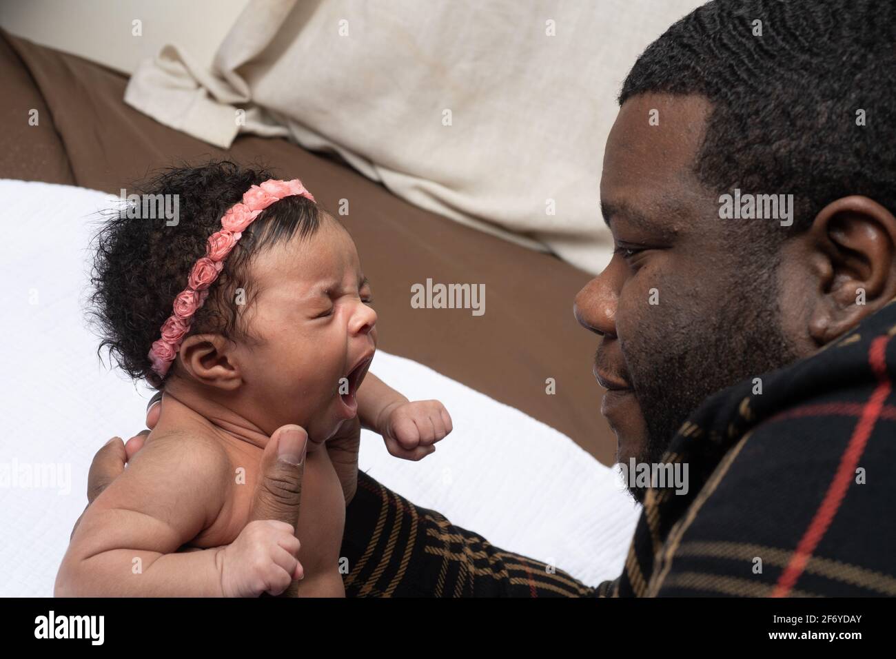 Neonato bambino ragazza 3 settimane, riflesso sbadigli tenuto da padre Foto Stock