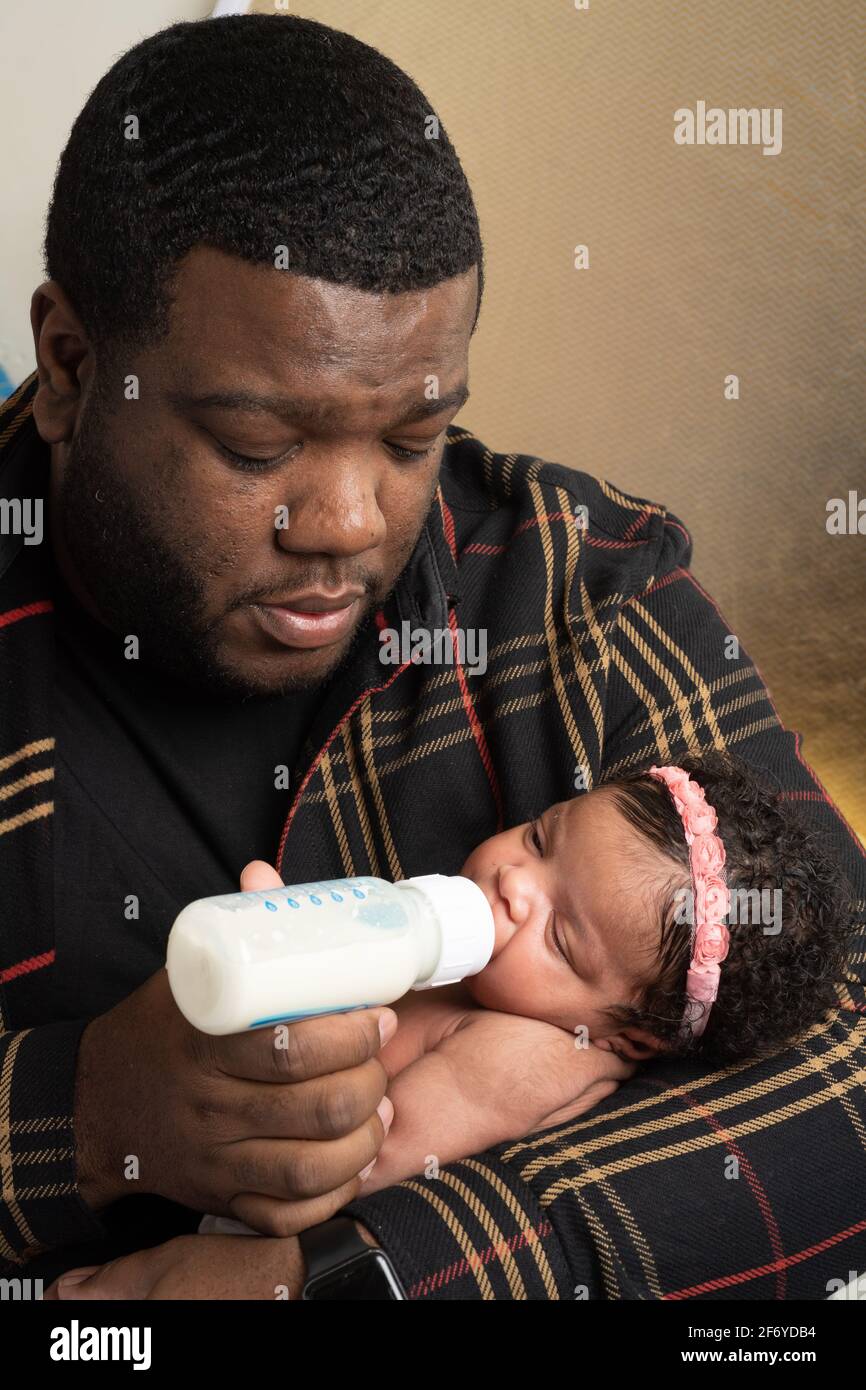 Bambina neonato di 3 settimane, tenuta dal padre, biberon nutrito Foto Stock