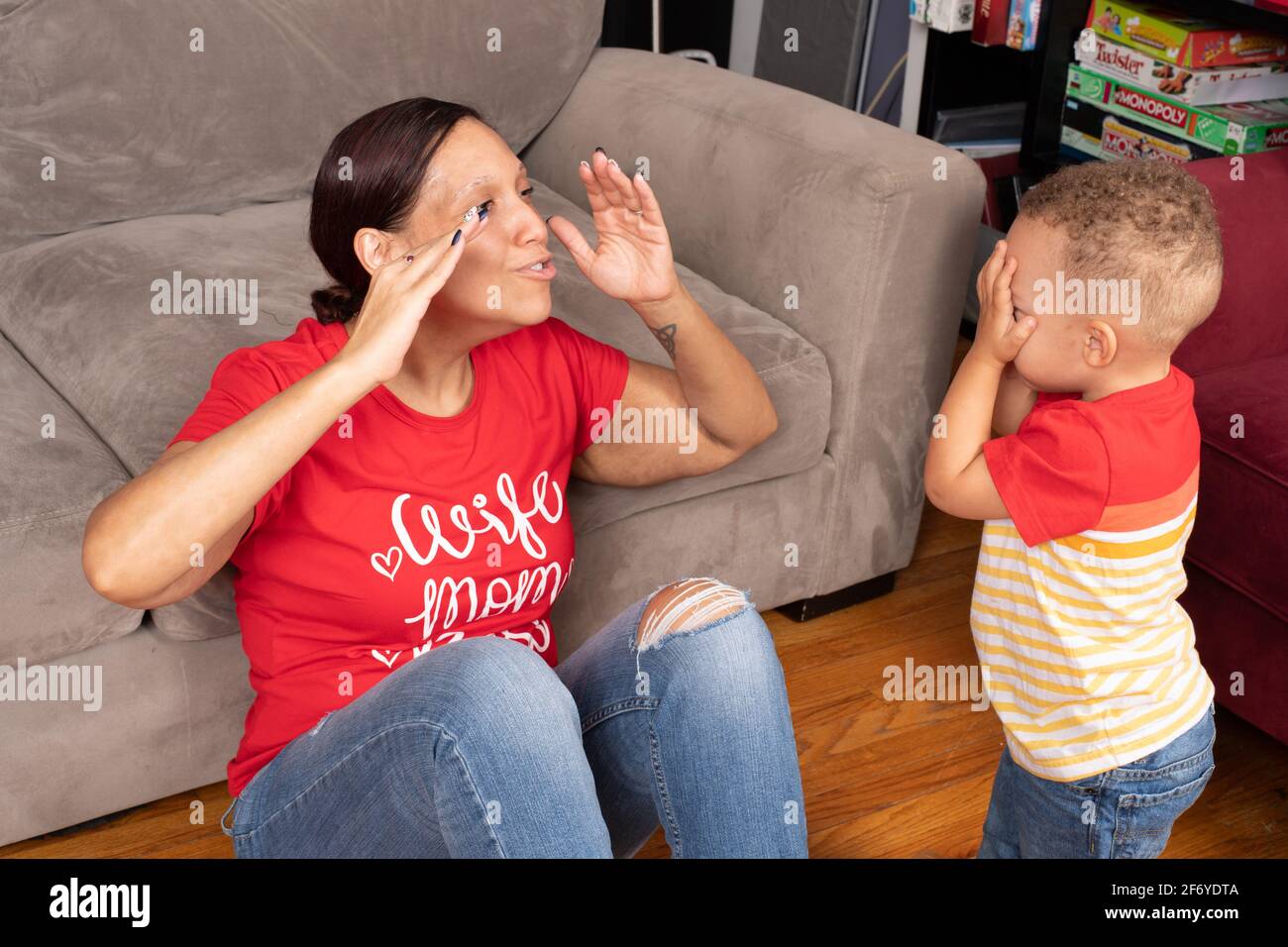 Madre che interagisce e gioca con il figlio di 2 anni, nascondersi e cercare in vista normale Foto Stock