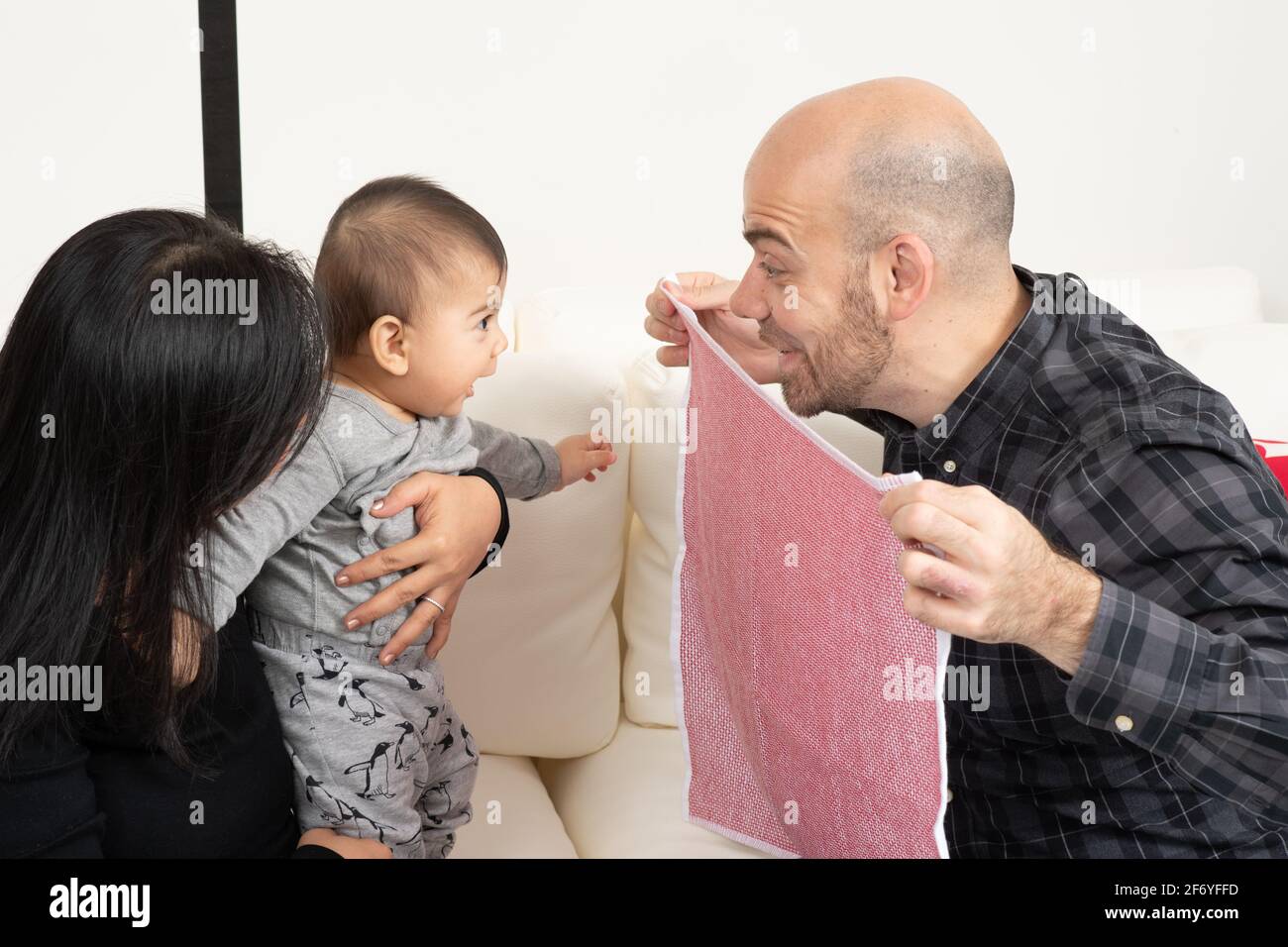 Sei mesi bambino ragazzo dare un'occhiata a un gioco boo con padre e madre Foto Stock