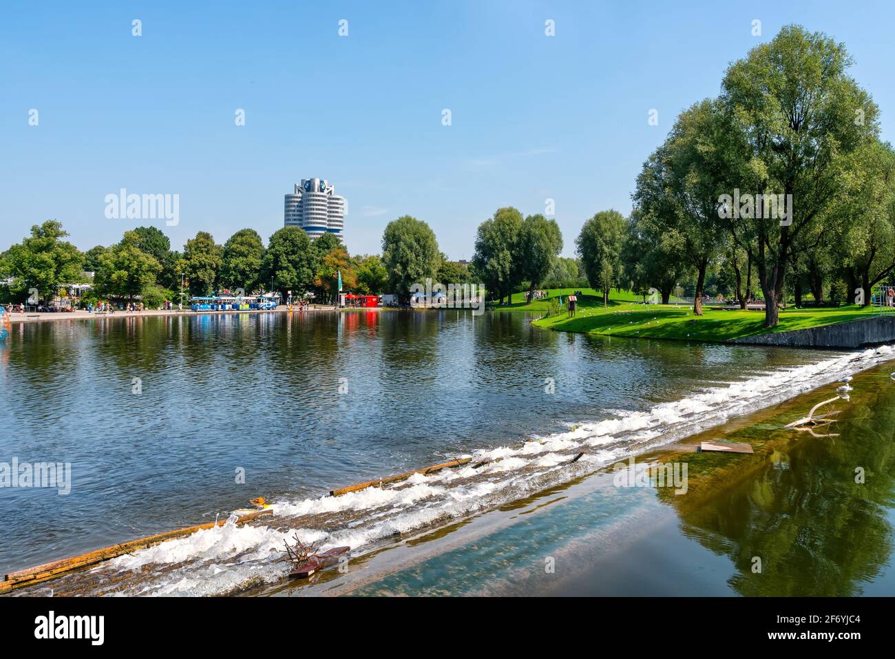 Monaco di Baviera, Germania, 08/24/2019: Parco olimpico con laghetto, prati e alberi. Sullo sfondo l'edificio BMW Foto Stock