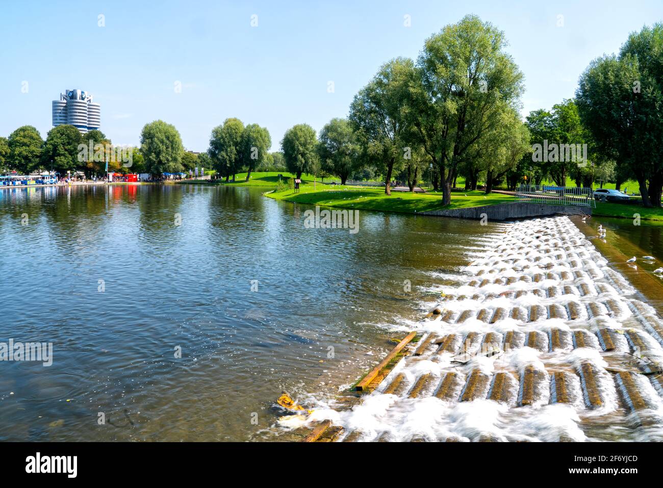Monaco di Baviera, Germania, 08/24/2019: Parco olimpico con laghetto, prati e alberi. Sullo sfondo l'edificio BMW Foto Stock