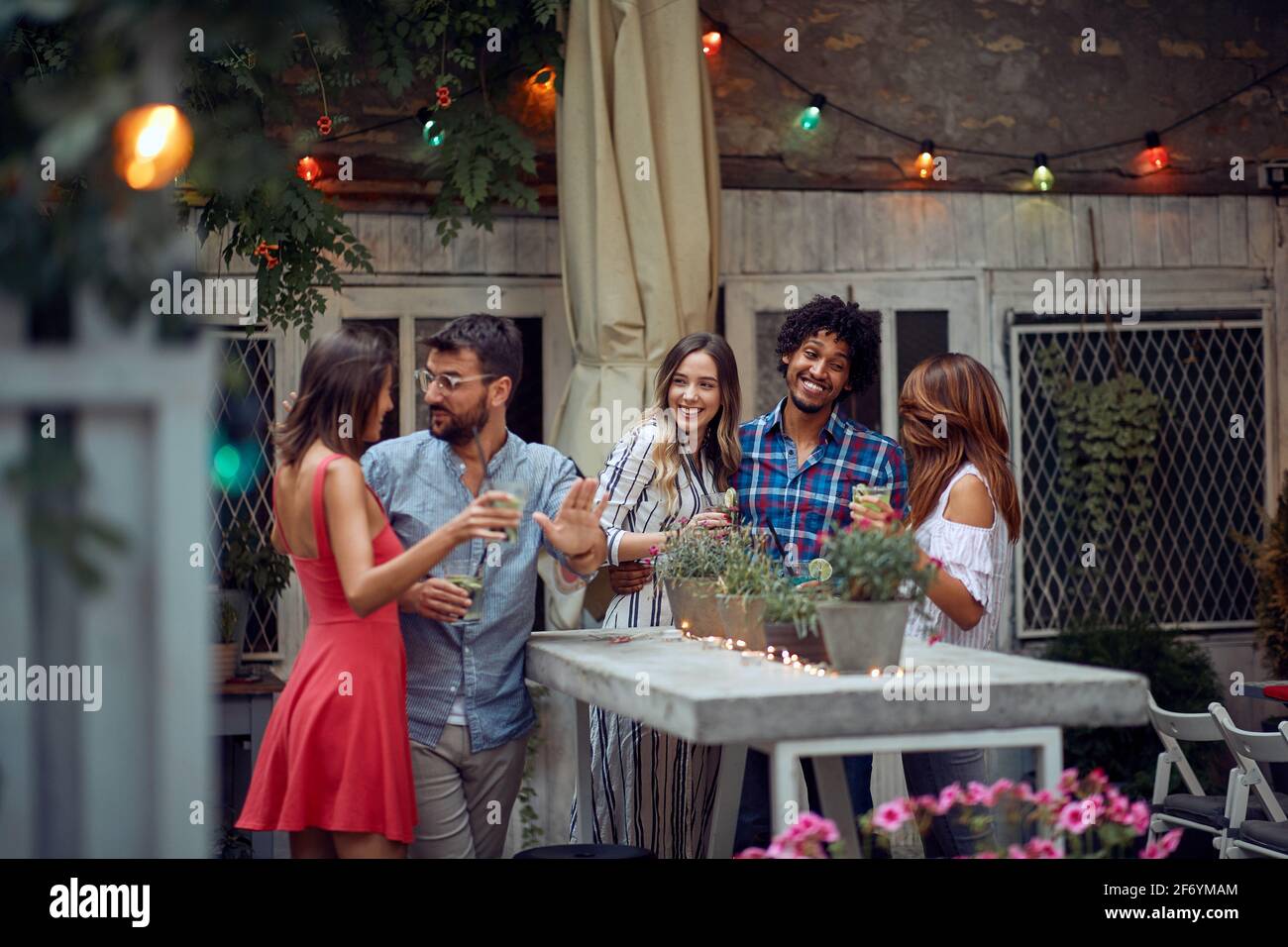 Amici allegri che chiacchierano al party di compleanno all'aperto in un bellissimo tramonto estivo. Tempo di amicizia di qualità insieme Foto Stock