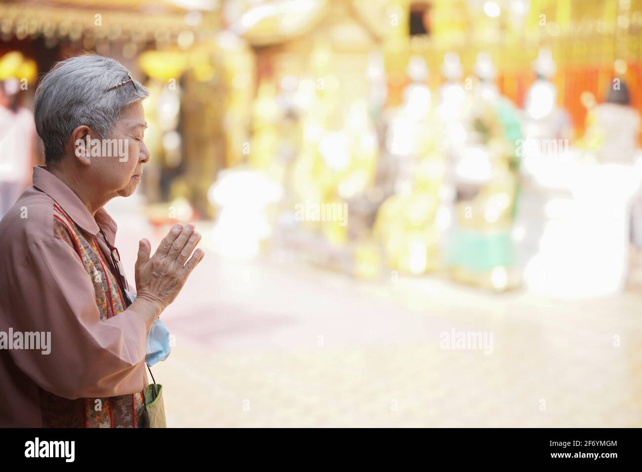 anziana anziana asiatica anziana viaggiatore turista in preghiera al tempio buddista. Foto Stock