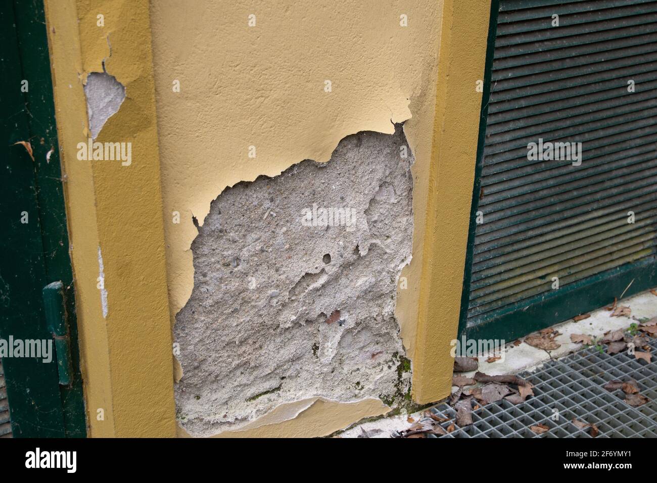 Kaputte Fassade, abbröckelnder Putz auf gelber Mauer Foto Stock