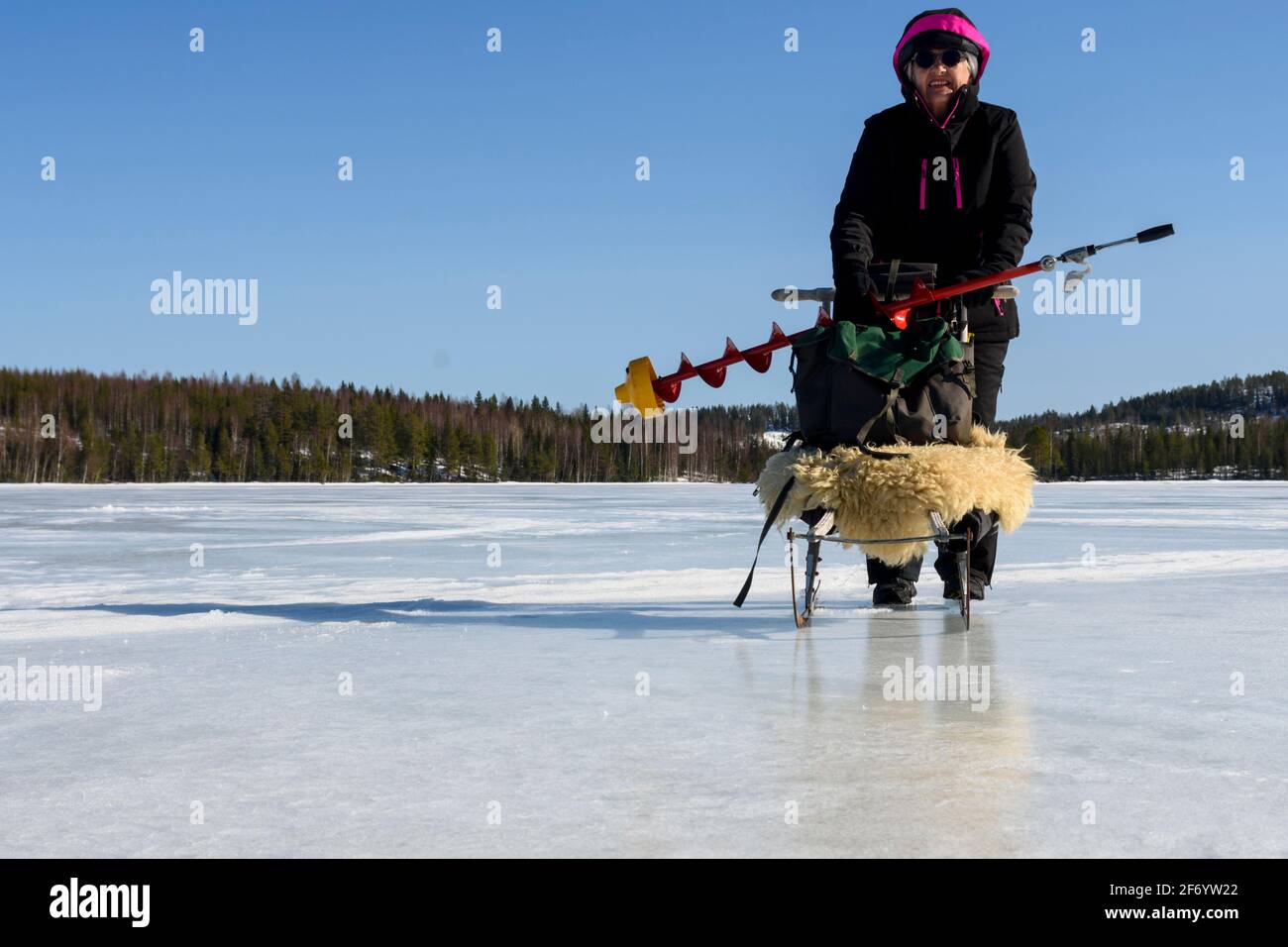 Donne su un lago con un veicolo speciale (kicksled) caricato con ghiaccio trapano e zaino in spalla, con un cielo blu in background, foto da Vasternorrland Swe Foto Stock