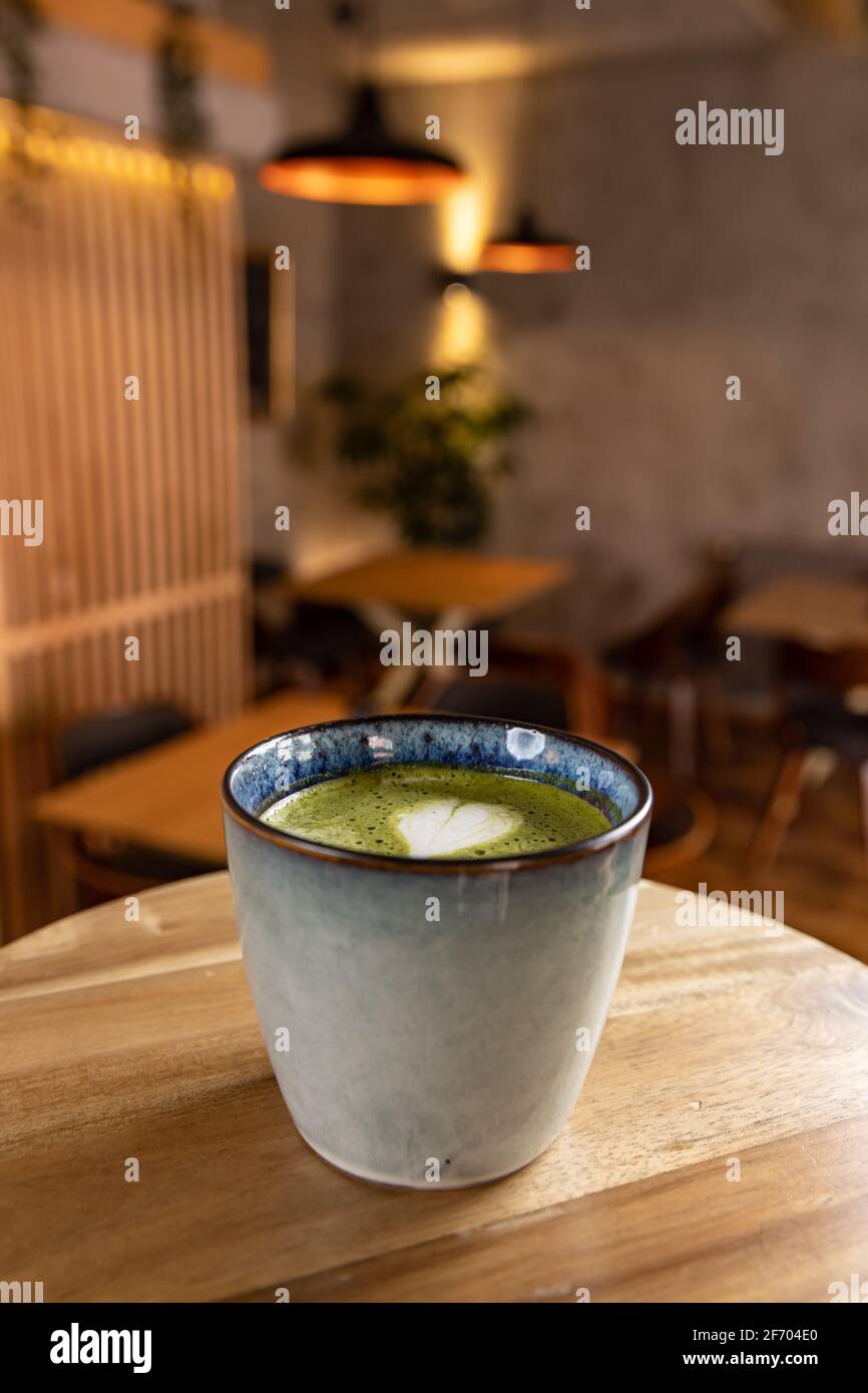 Tazza di latte matcha sul tavolo sfocato ristorante interno caffè sfondo Foto Stock