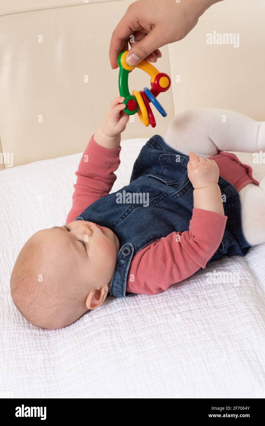 4 mesi ragazza del bambino closeup sul posteriore che raggiunge per giocattolo svincolato Foto Stock
