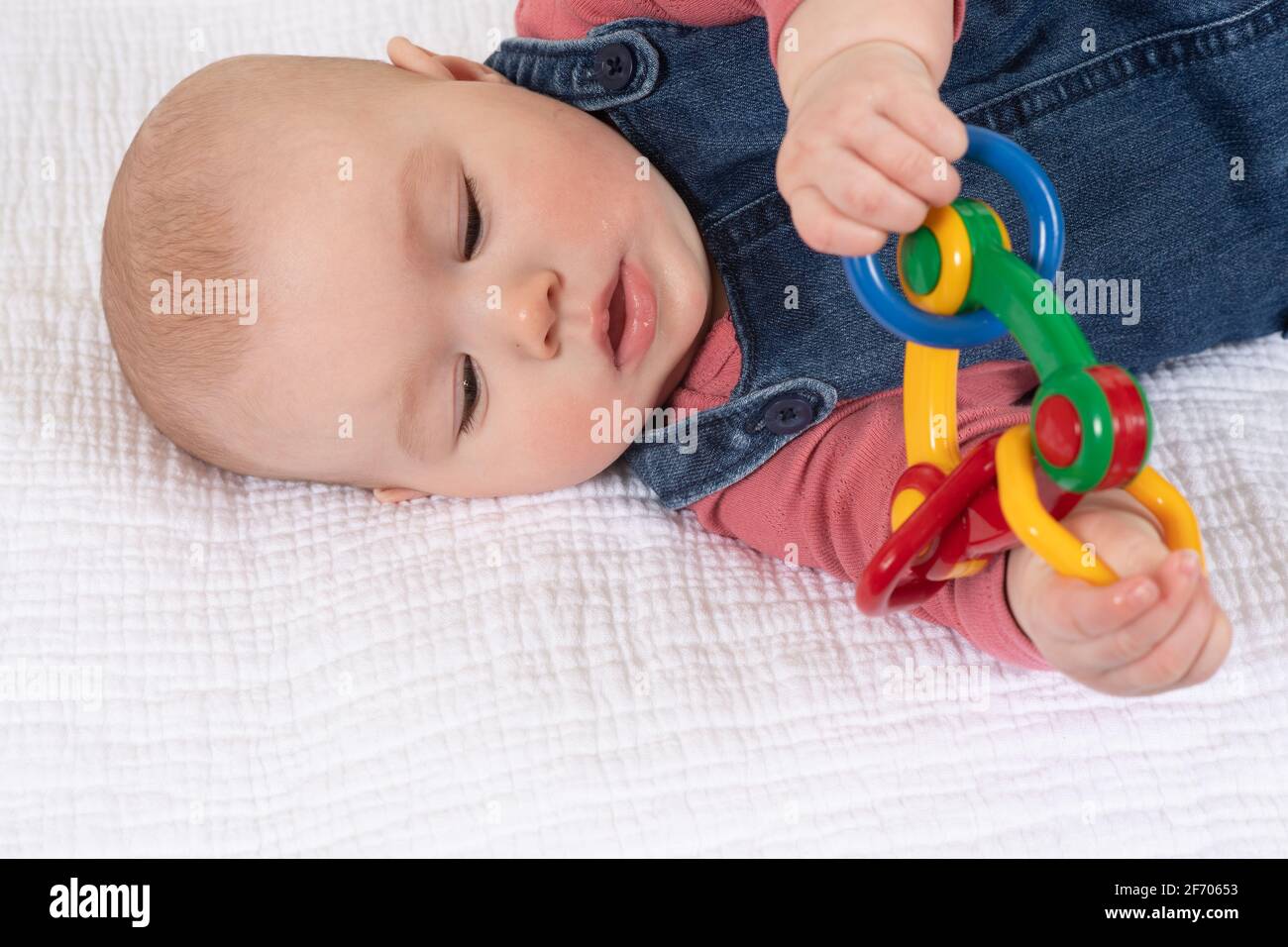 bambina di 4 mesi, tenendo il giocattolo con entrambe le mani Foto Stock