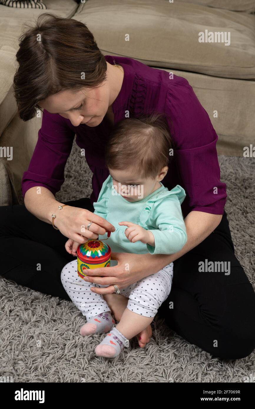 bambina di 10 mesi con madre, ha mostrato come il giocattolo musicale con manovella funziona Foto Stock